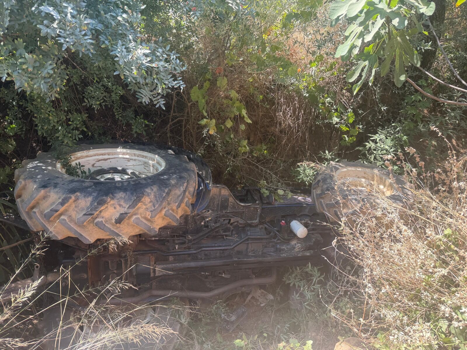 Devrilen traktörün altında kalan sürücüyü itfaiyeciler kurtardı